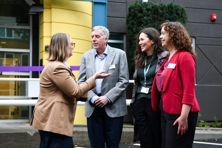 Four individuals talking in front of The Way Station after it officially opened.